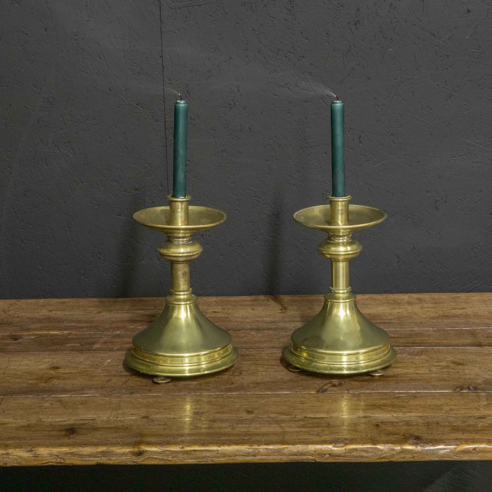 A pair of Victorian solid brass pricket candlesticks featuring wide circular drip pans, turned knopped stems, and broad bell-shaped bases. View IV