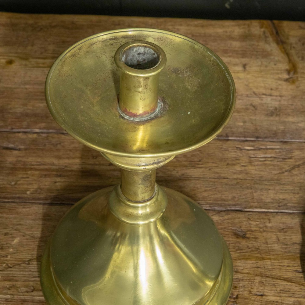A pair of Victorian solid brass pricket candlesticks featuring wide circular drip pans, turned knopped stems, and broad bell-shaped bases. View V