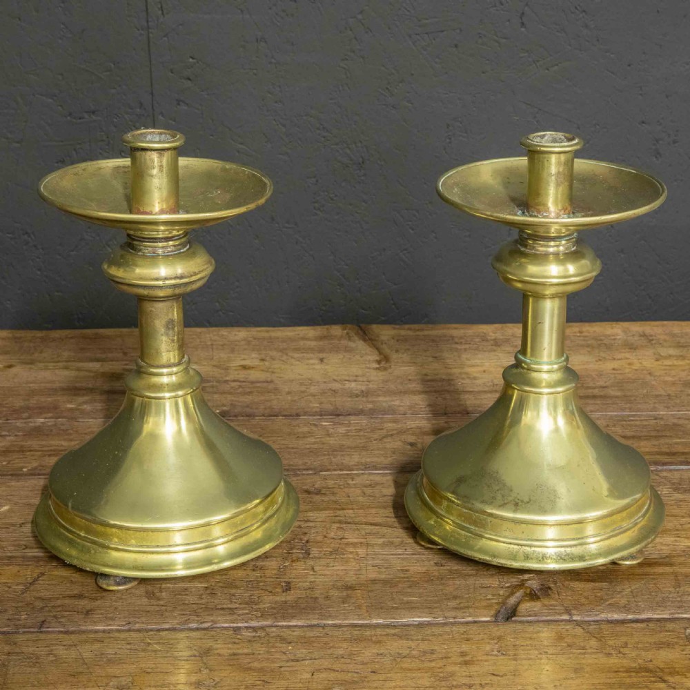 A pair of Victorian solid brass pricket candlesticks featuring wide circular drip pans, turned knopped stems, and broad bell-shaped bases. View VI