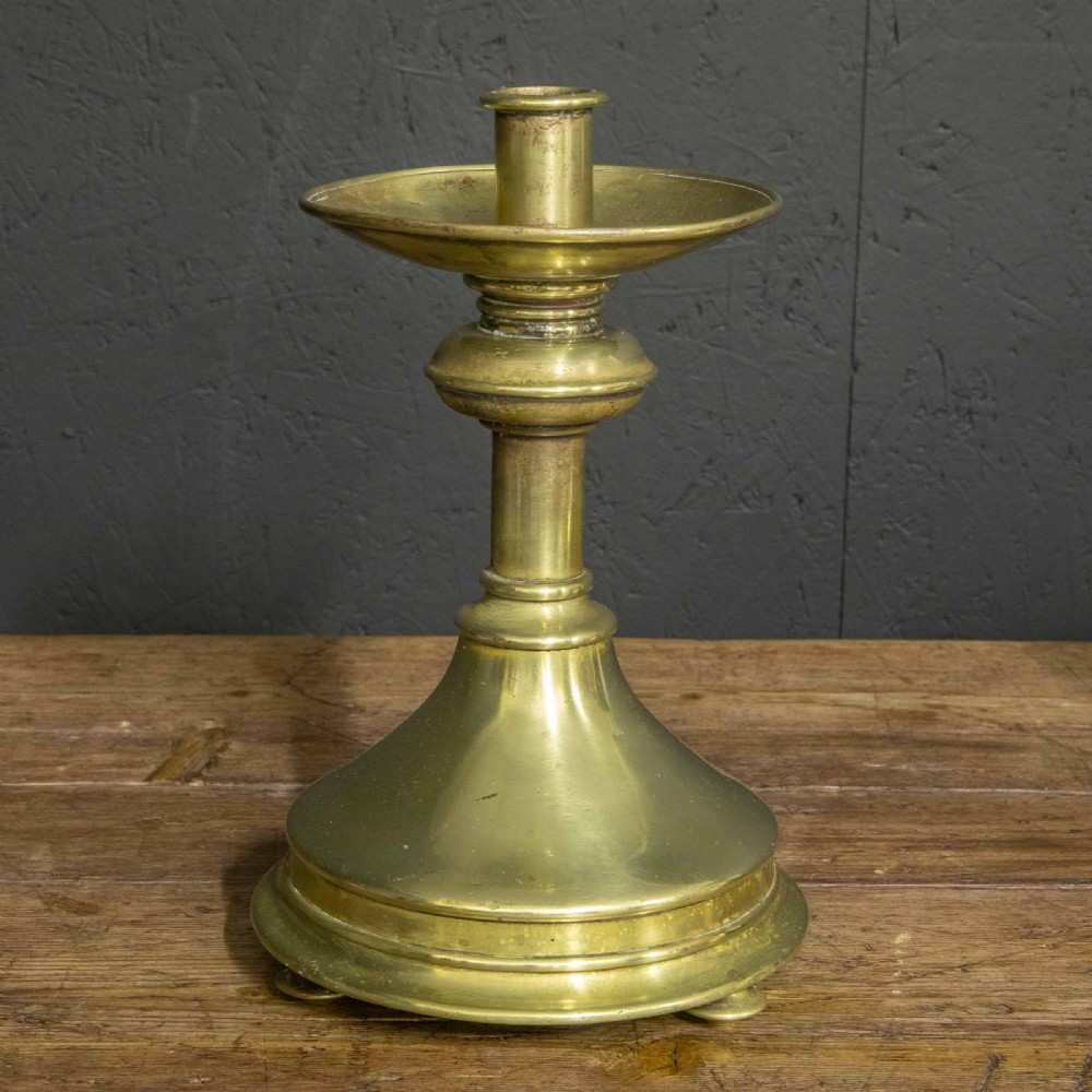 A pair of Victorian solid brass pricket candlesticks featuring wide circular drip pans, turned knopped stems, and broad bell-shaped bases. View X