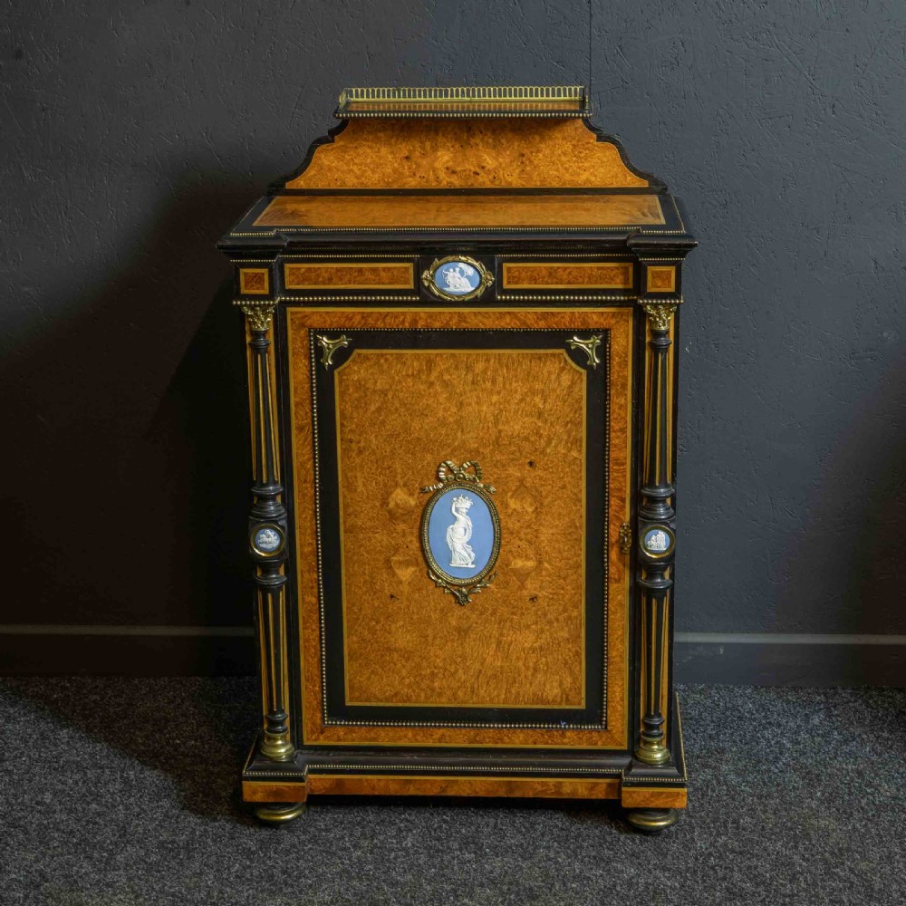 A pair of Victorian ebonised and amboyna pier cabinets featuring raised brass galleries and central blue porcelain Jasperware plaques. View IV
