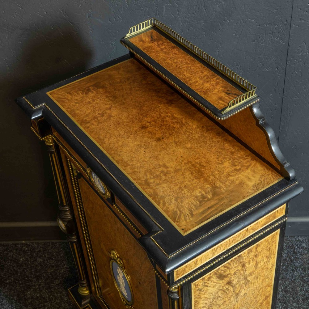 A pair of Victorian ebonised and amboyna pier cabinets featuring raised brass galleries and central blue porcelain Jasperware plaques. View VII