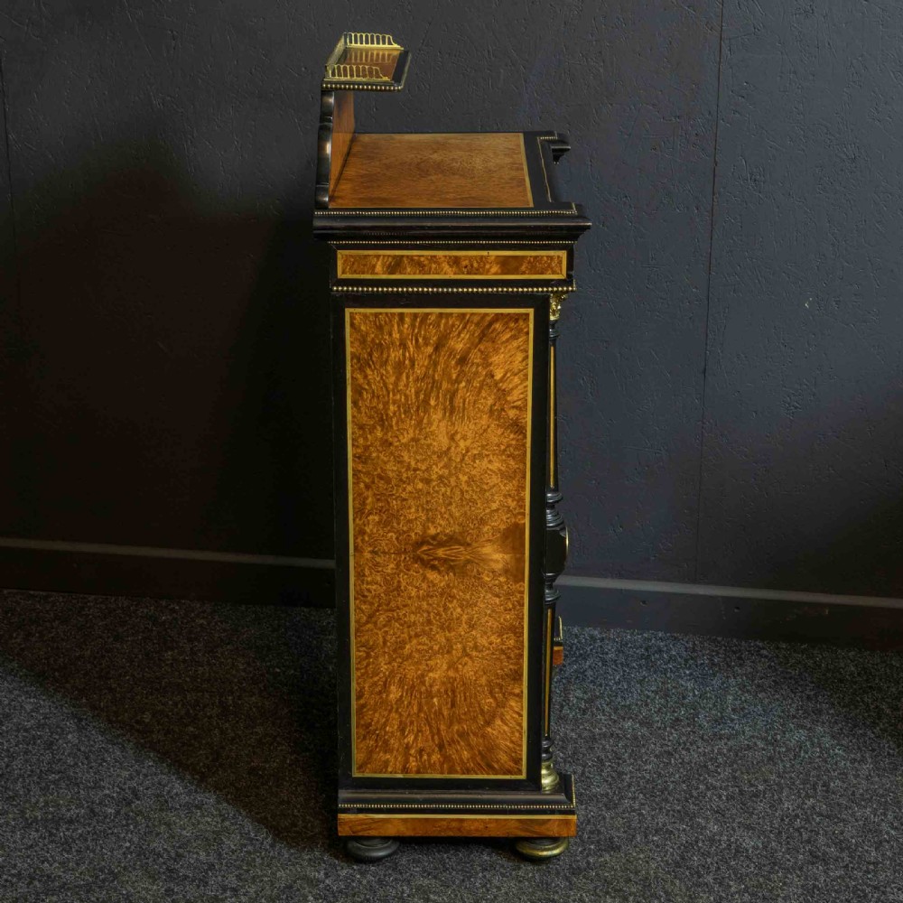 A pair of Victorian ebonised and amboyna pier cabinets featuring raised brass galleries and central blue porcelain Jasperware plaques. View IX