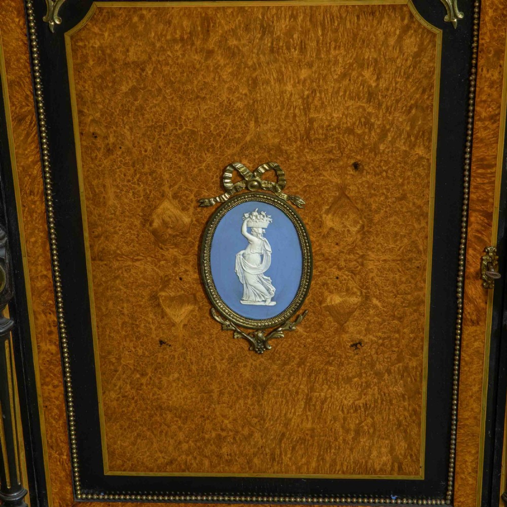 A pair of Victorian ebonised and amboyna pier cabinets featuring raised brass galleries and central blue porcelain Jasperware plaques. View XIV