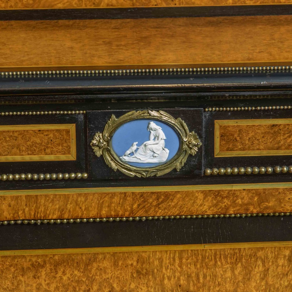 A pair of Victorian ebonised and amboyna pier cabinets featuring raised brass galleries and central blue porcelain Jasperware plaques. View XV