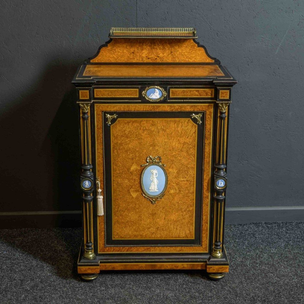 A pair of Victorian ebonised and amboyna pier cabinets featuring raised brass galleries and central blue porcelain Jasperware plaques. View XX