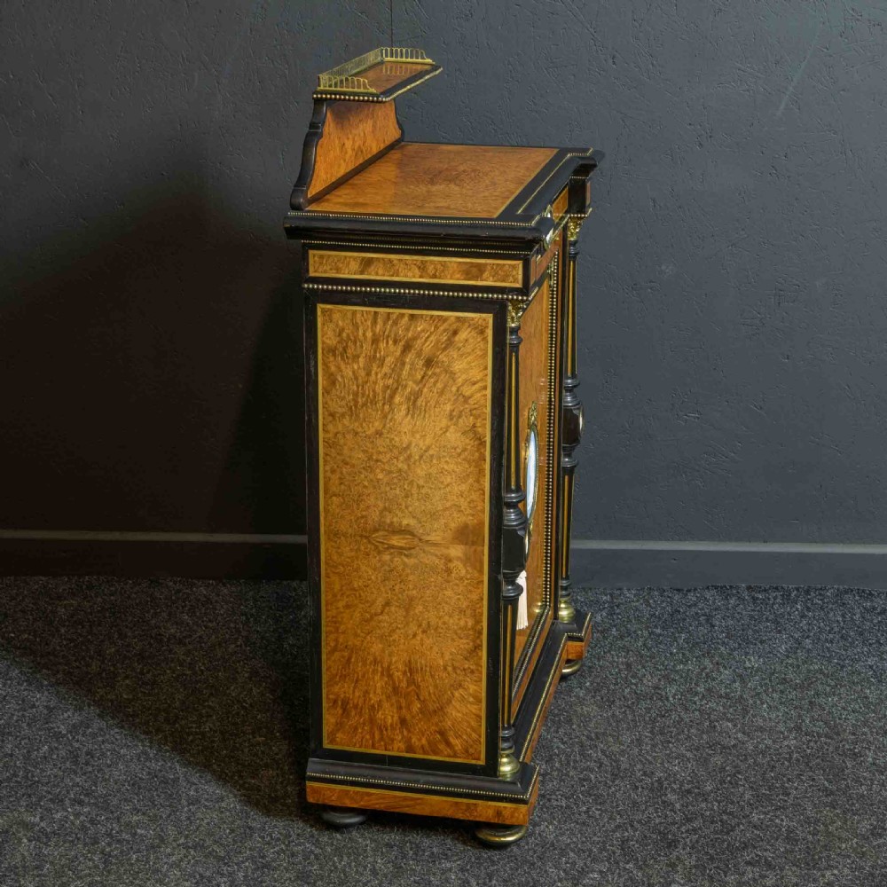 A pair of Victorian ebonised and amboyna pier cabinets featuring raised brass galleries and central blue porcelain Jasperware plaques. View XXII