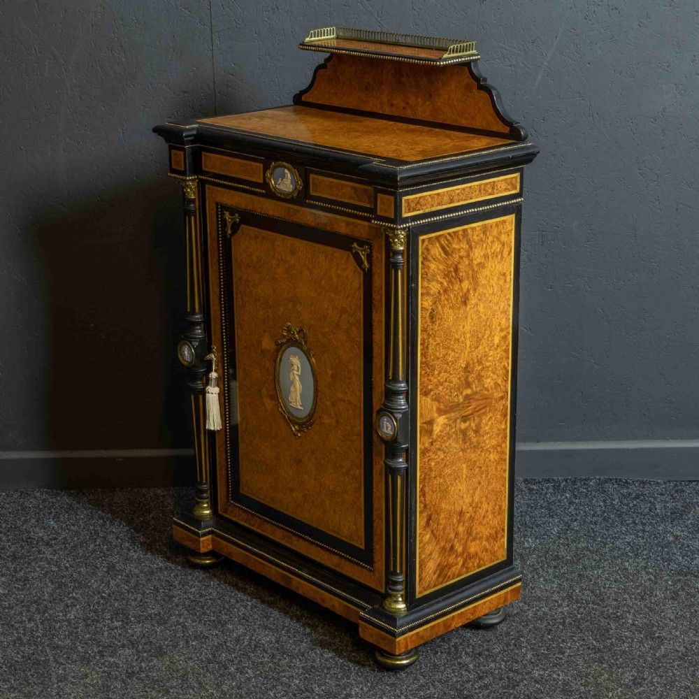 A pair of Victorian ebonised and amboyna pier cabinets featuring raised brass galleries and central blue porcelain Jasperware plaques. View XXIII