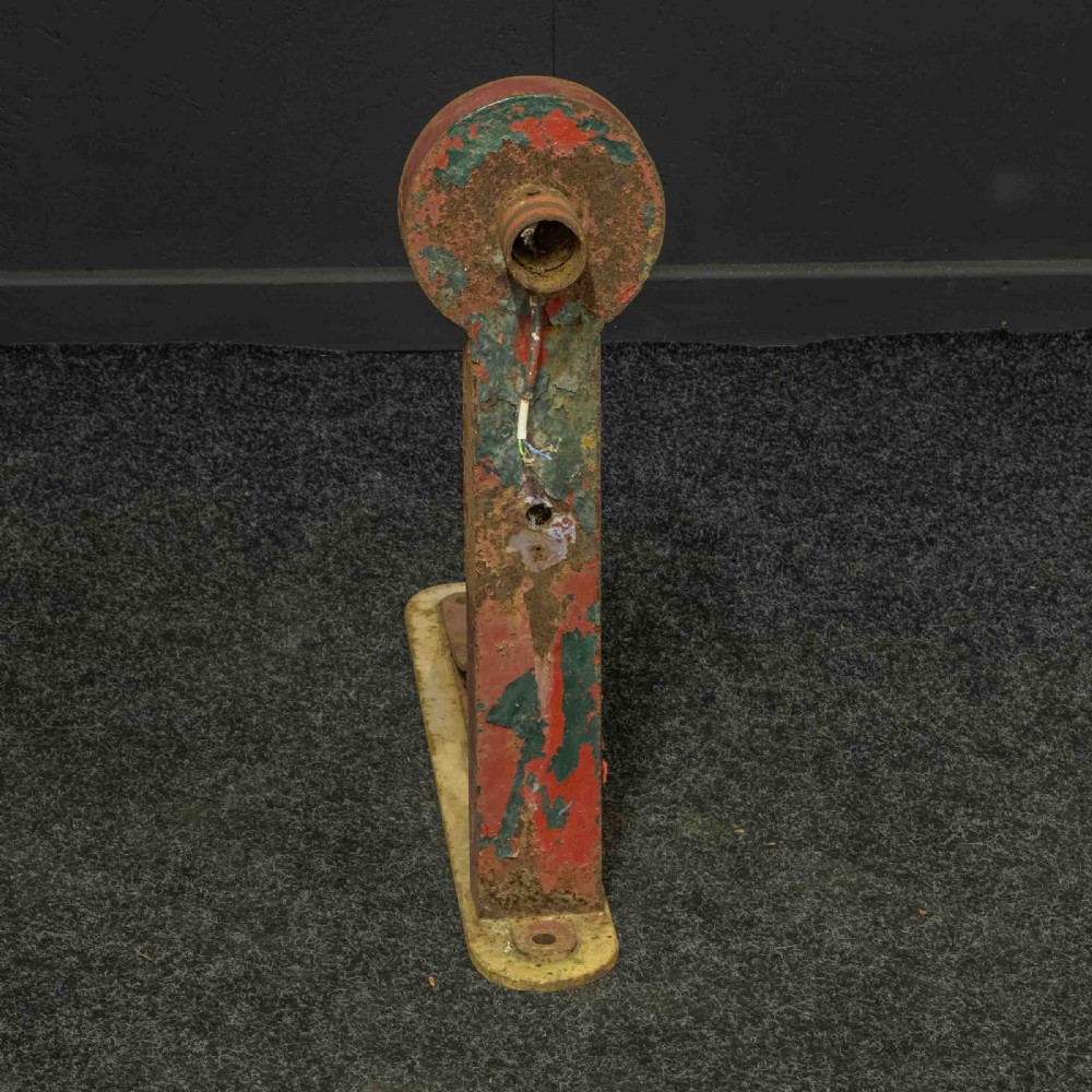 A heavy red painted cast iron wall bracket with a curved support bar and circular motif, showing distressed paint and metal details. View IV