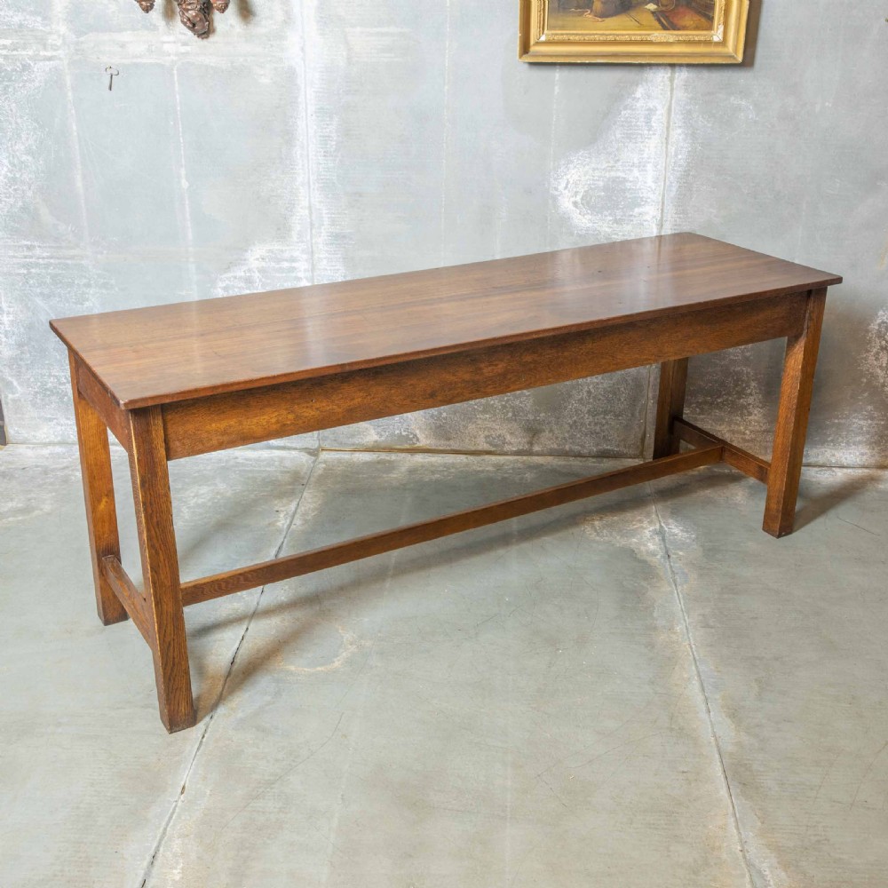 A long, tall oak refectory table featuring three frieze drawers with brass handles, straight legs, and a low H-stretcher base. View VIII