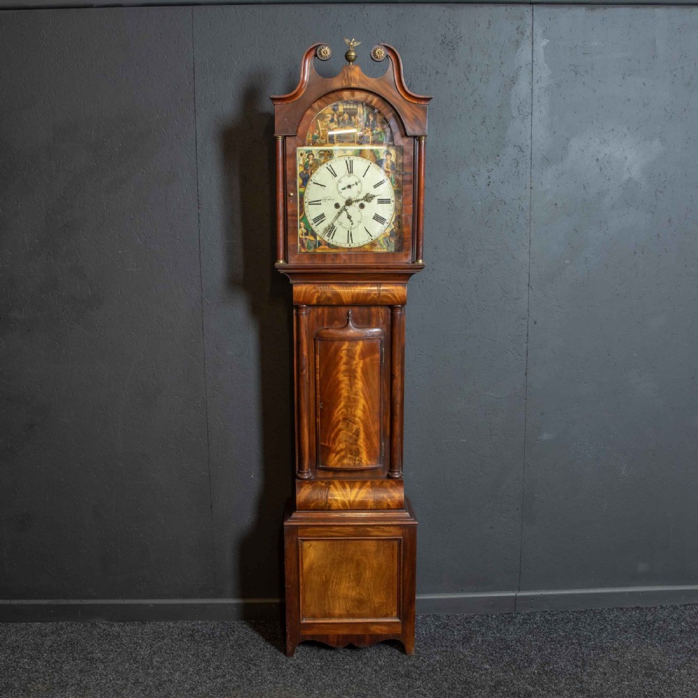 An antique Scottish mahogany longcase clock featuring a swan neck pediment, turned hood columns, flame mahogany trunk door, and a hand-painted dial.