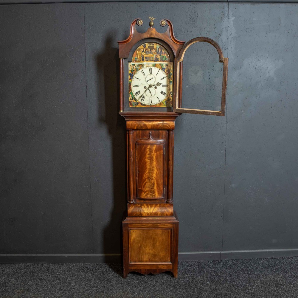 An antique Scottish mahogany longcase clock featuring a swan neck pediment, turned hood columns, flame mahogany trunk door, and a hand-painted dial. View II