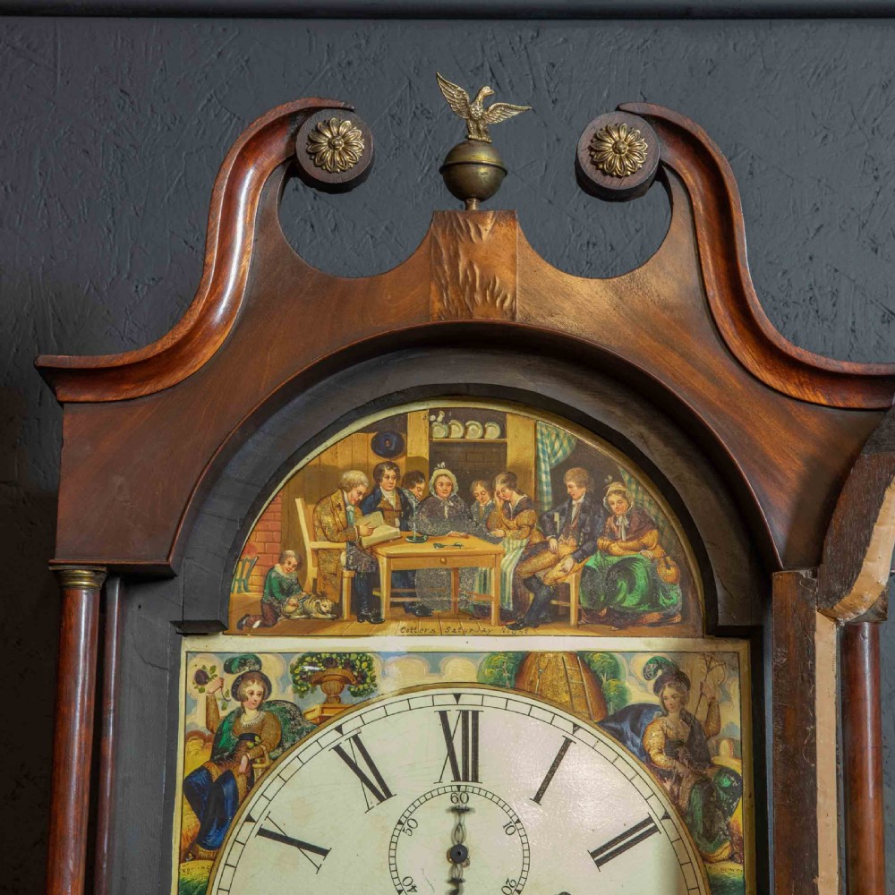 An antique Scottish mahogany longcase clock featuring a swan neck pediment, turned hood columns, flame mahogany trunk door, and a hand-painted dial. View V