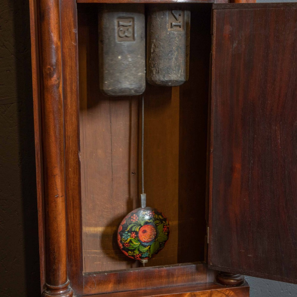 An antique Scottish mahogany longcase clock featuring a swan neck pediment, turned hood columns, flame mahogany trunk door, and a hand-painted dial. View X