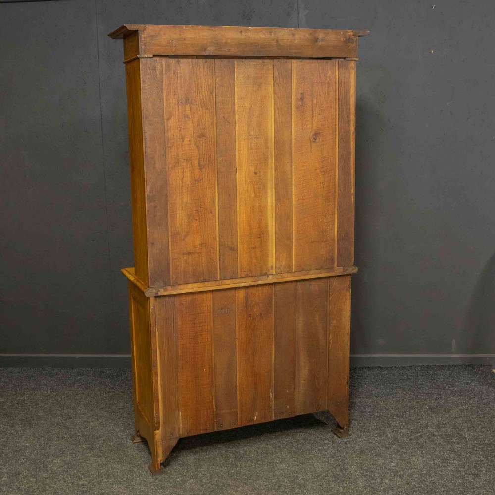 An Art Nouveau golden oak glazed bookcase featuring upper glass door panels and lower carved doors with stylised floral motifs. View IX