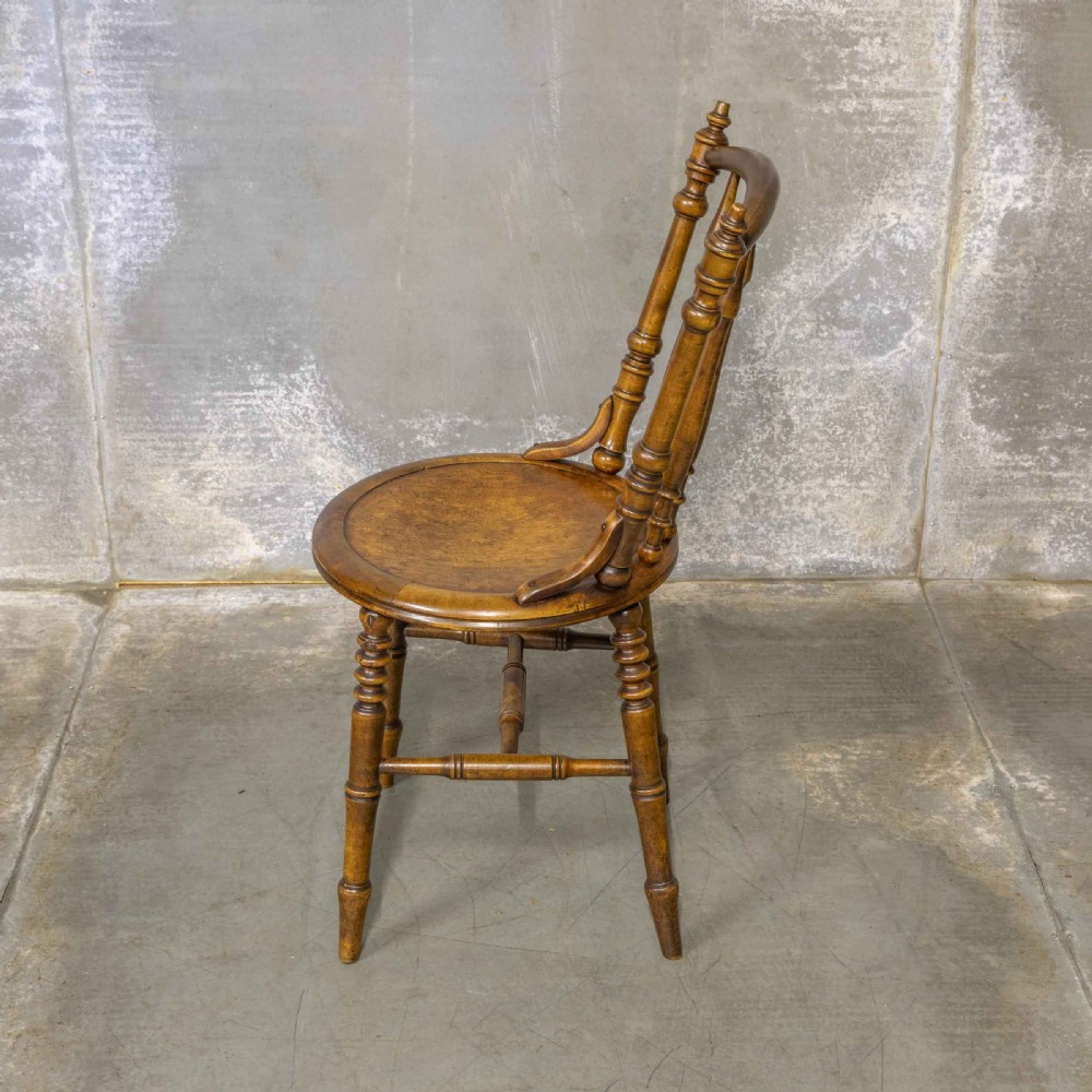A set of four warm brown wooden bentwood dining chairs featuring spindle backrests and circular seats. View IV