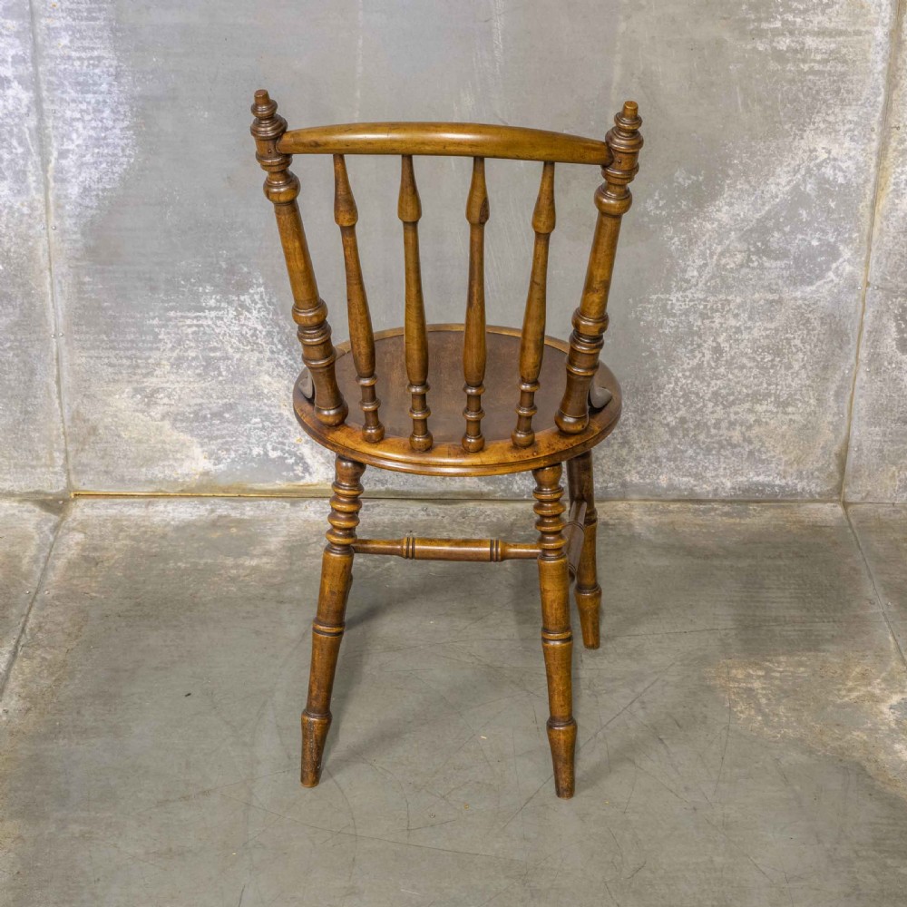 A set of four warm brown wooden bentwood dining chairs featuring spindle backrests and circular seats. View V