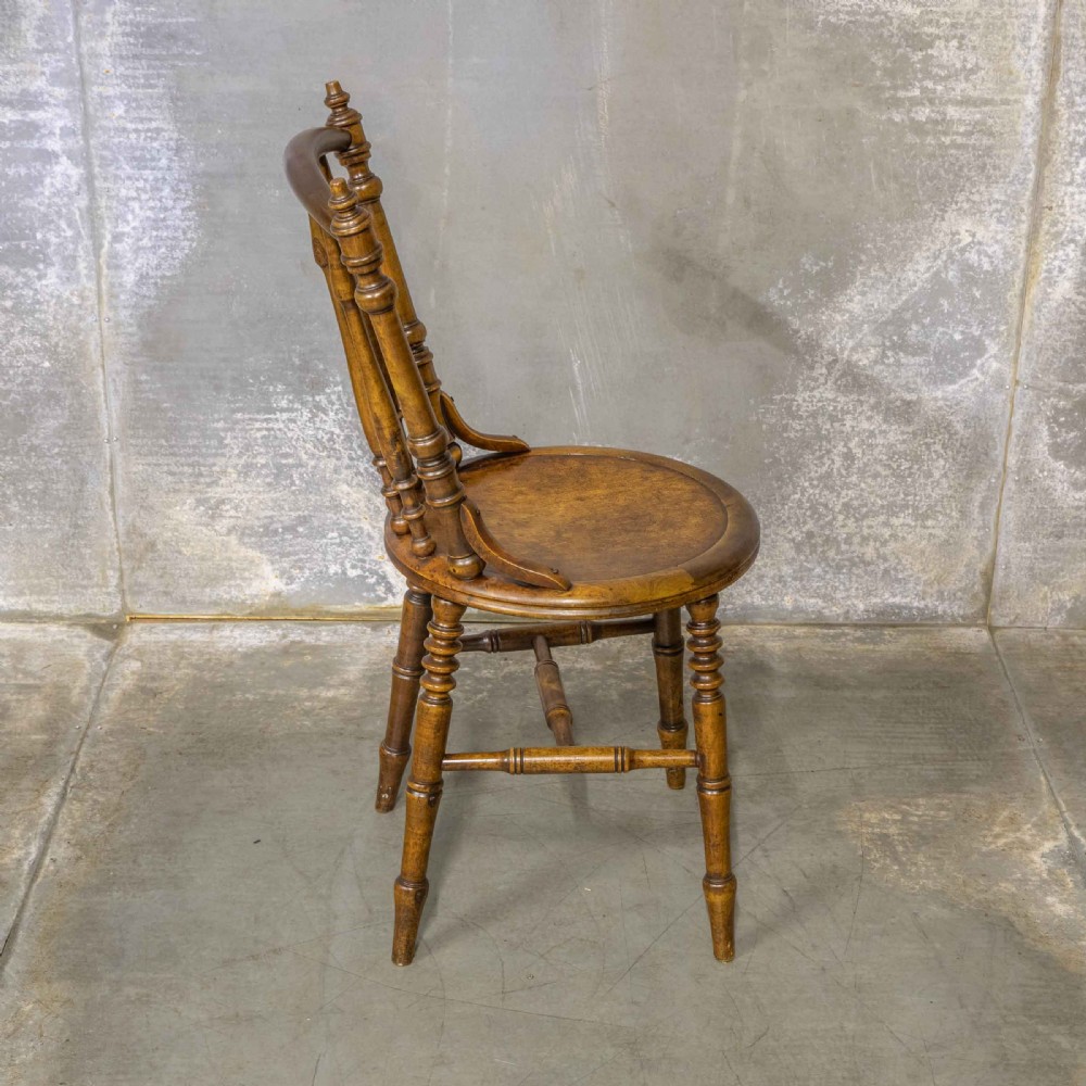 A set of four warm brown wooden bentwood dining chairs featuring spindle backrests and circular seats. View VI