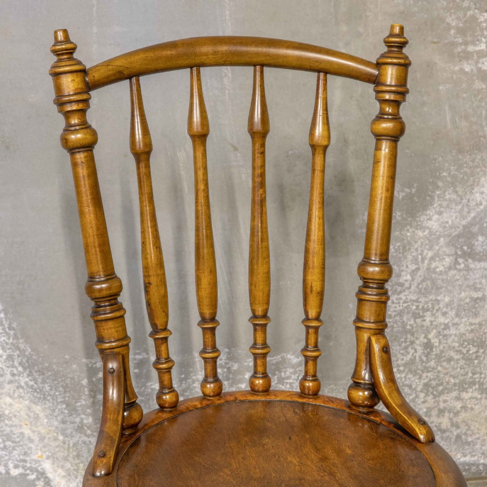A set of four warm brown wooden bentwood dining chairs featuring spindle backrests and circular seats. View VIII