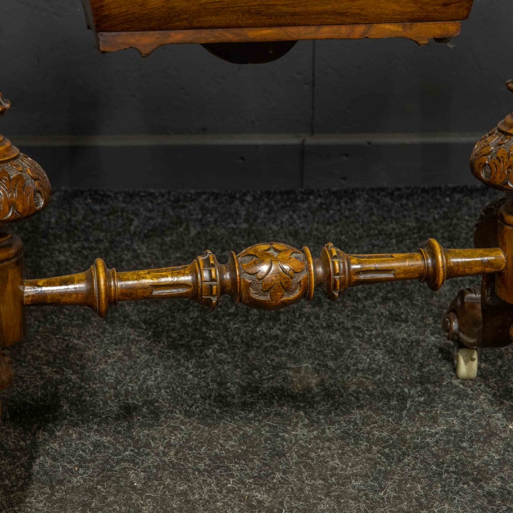 A Victorian burr walnut fold-over games and sewing table displaying an inlaid chess and backgammon board supported by carved pedestals, a stretcher base, and castors. View VIII