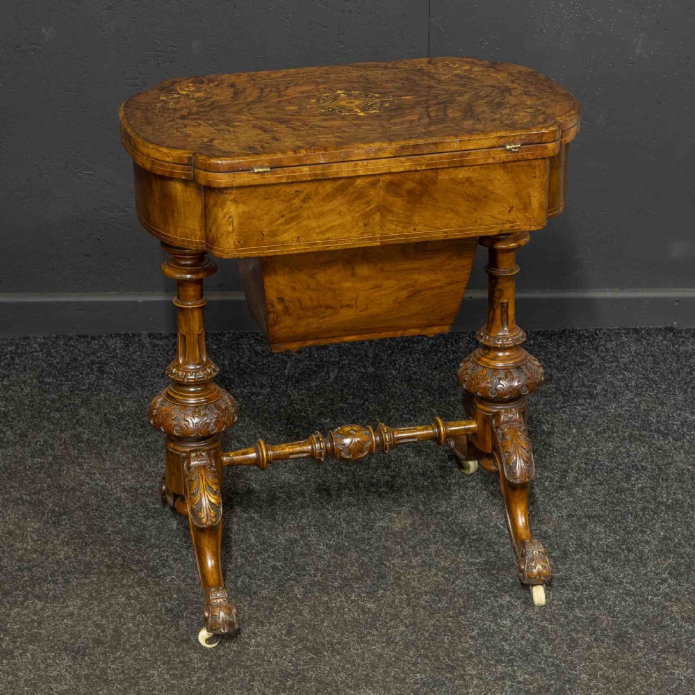 A Victorian burr walnut fold-over games and sewing table displaying an inlaid chess and backgammon board supported by carved pedestals, a stretcher base, and castors. View XI