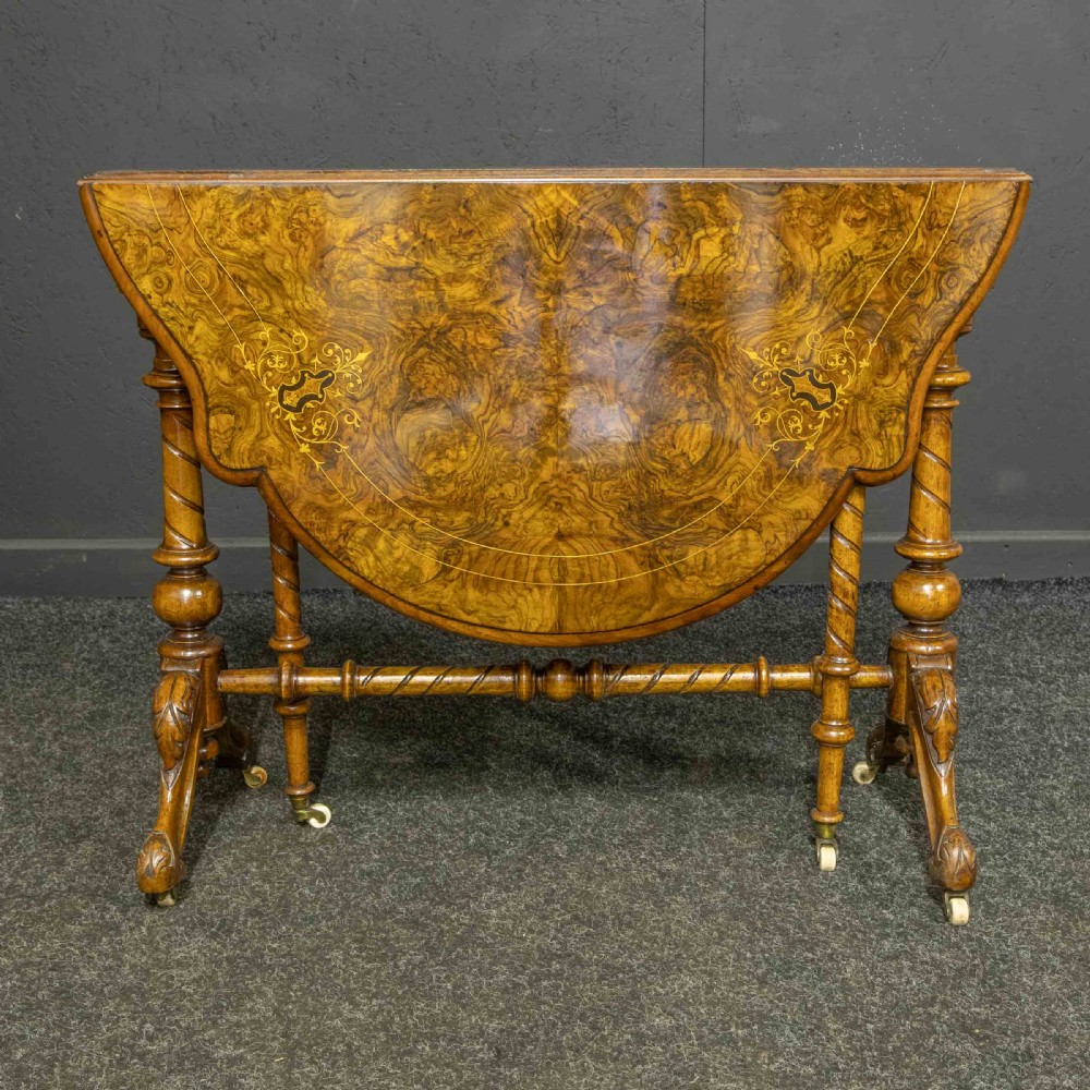 A Victorian burr walnut Sutherland drop-leaf table featuring detailed marquetry inlay, turned legs, and ceramic castors. View IV