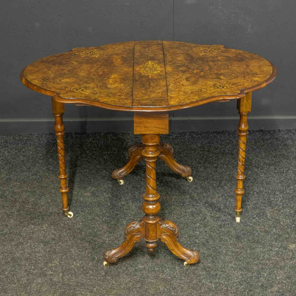 A Victorian burr walnut Sutherland drop-leaf table featuring detailed marquetry inlay, turned legs, and ceramic castors. View VII