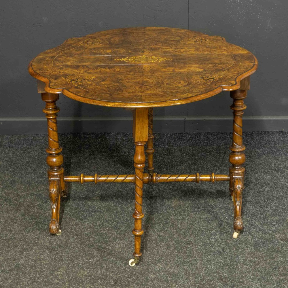 A Victorian burr walnut Sutherland drop-leaf table featuring detailed marquetry inlay, turned legs, and ceramic castors. View VIII