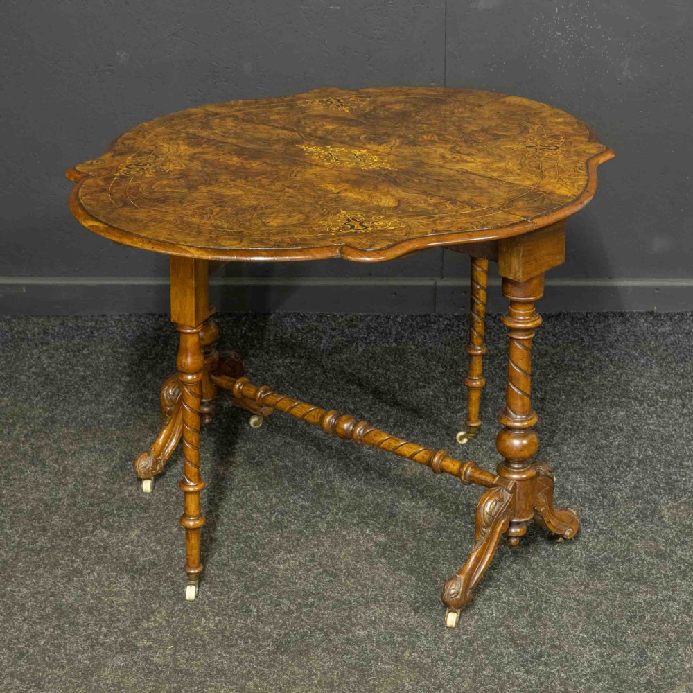 A Victorian burr walnut Sutherland drop-leaf table featuring detailed marquetry inlay, turned legs, and ceramic castors. View IX