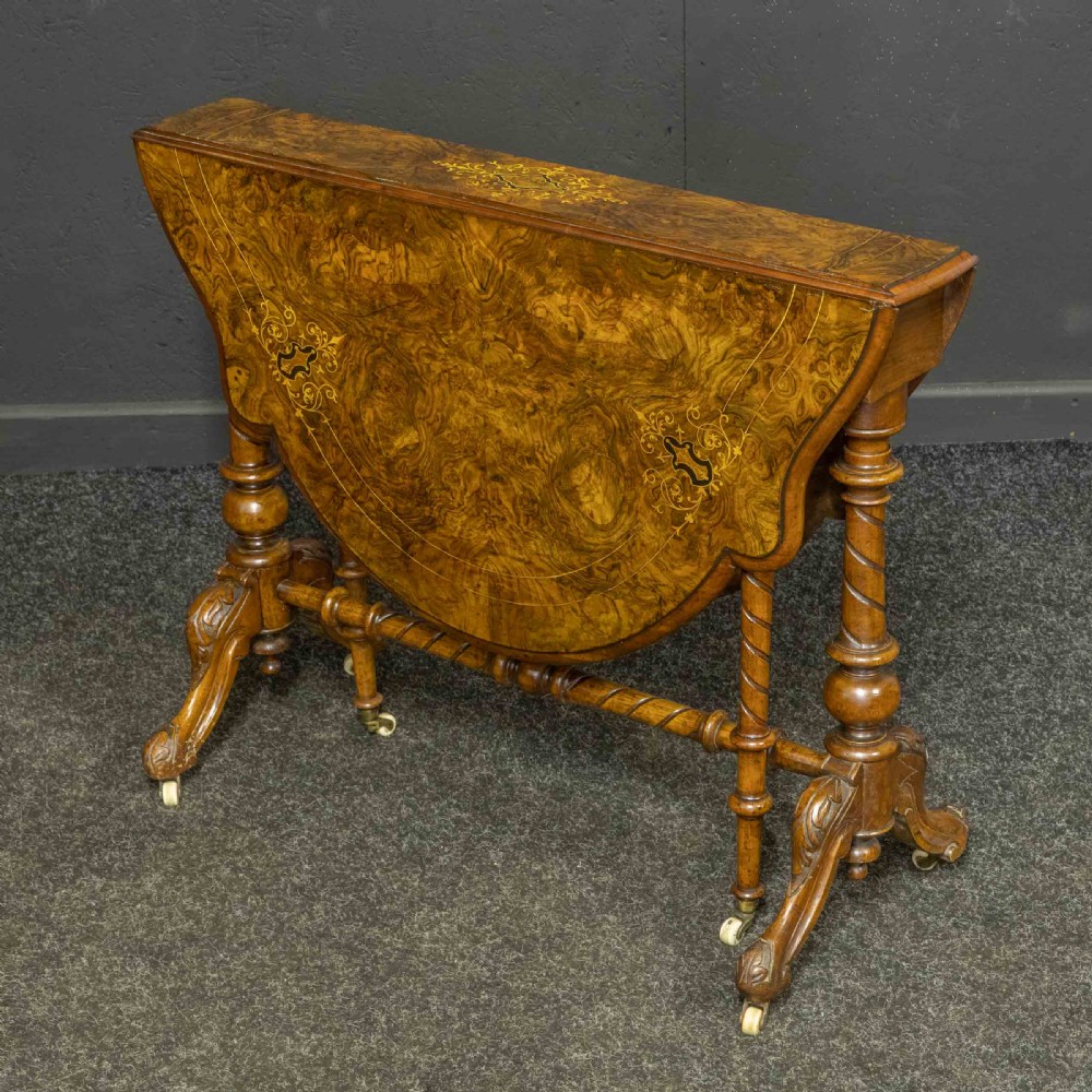 A Victorian burr walnut Sutherland drop-leaf table featuring detailed marquetry inlay, turned legs, and ceramic castors. View XII