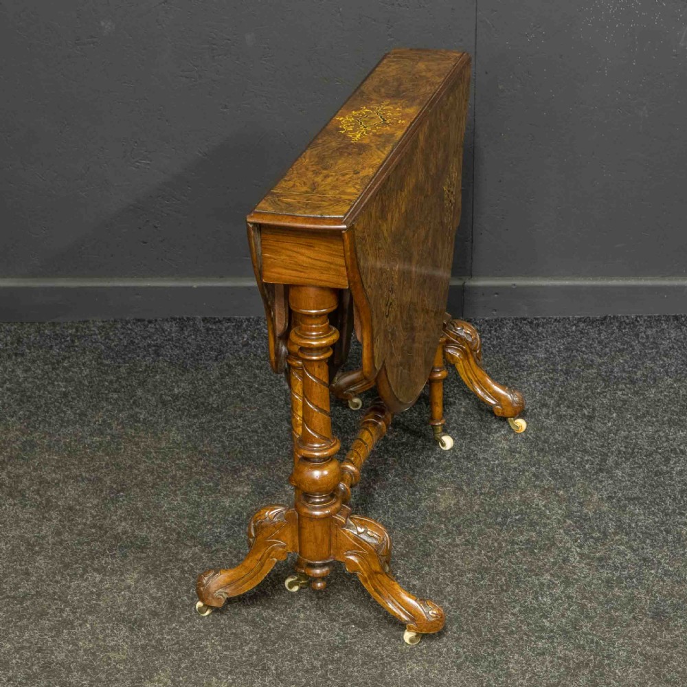 A Victorian burr walnut Sutherland drop-leaf table featuring detailed marquetry inlay, turned legs, and ceramic castors. View XIII