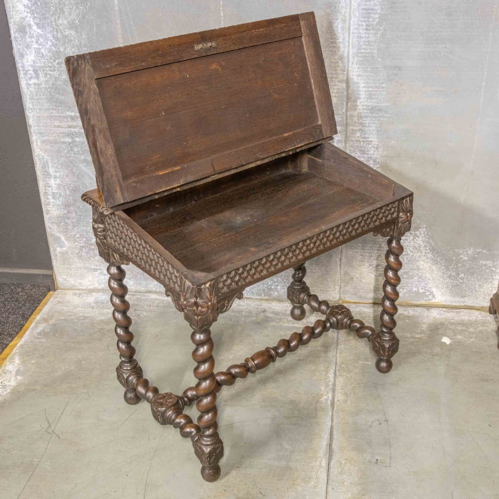 A Victorian carved oak writing desk featuring a sloped red leather surface, barley twist legs, and carved gallery details. View V