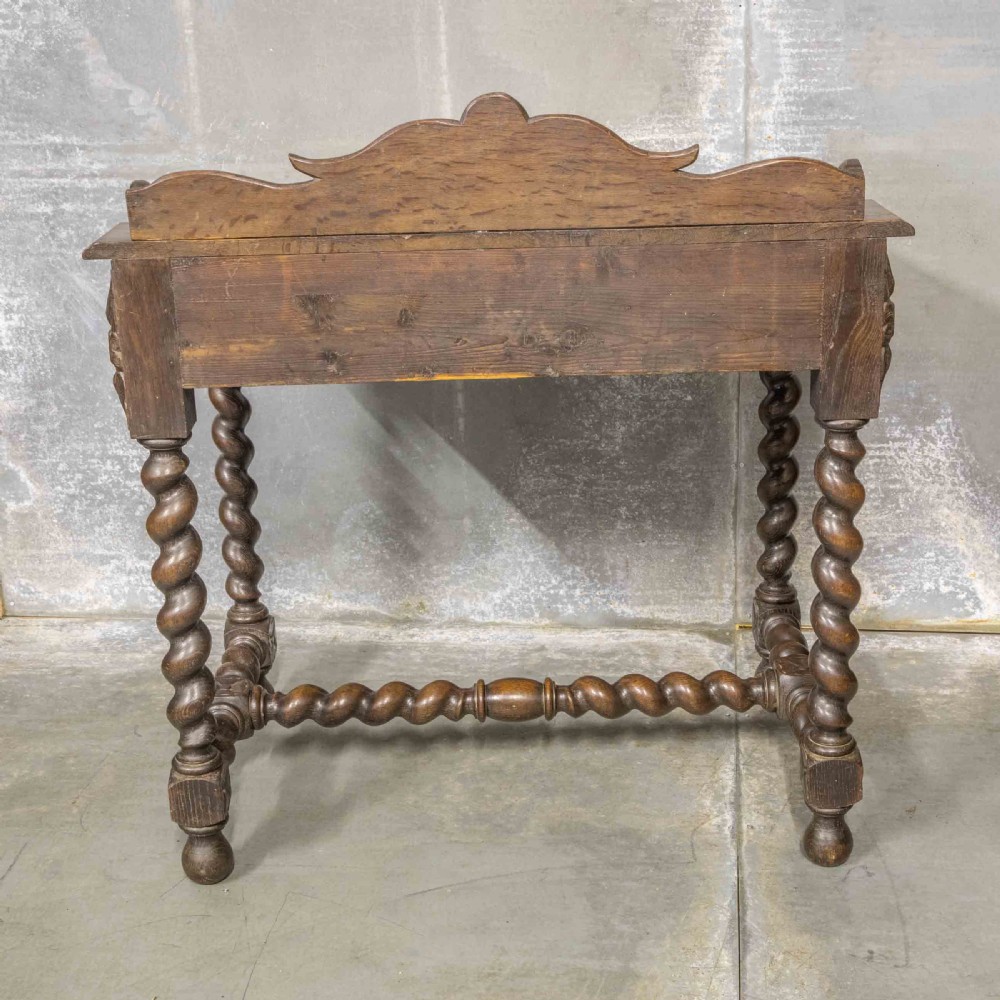A Victorian carved oak writing desk featuring a sloped red leather surface, barley twist legs, and carved gallery details. View VIII