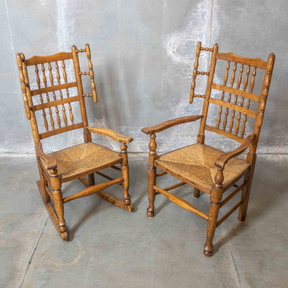 A pair of matching Victorian country armchairs in warm wood with woven rush seats and turned spindle backs, including one rocking chair and one static armchair.