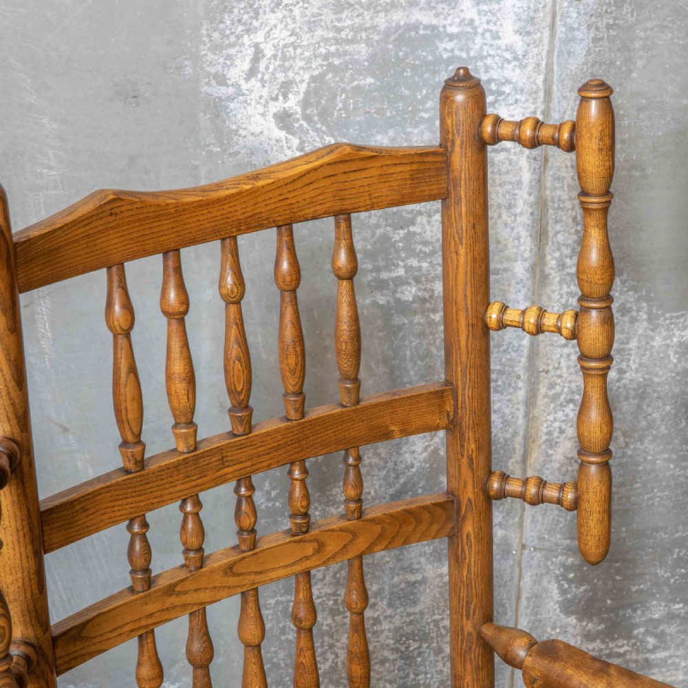 A pair of matching Victorian country armchairs in warm wood with woven rush seats and turned spindle backs, including one rocking chair and one static armchair. View V