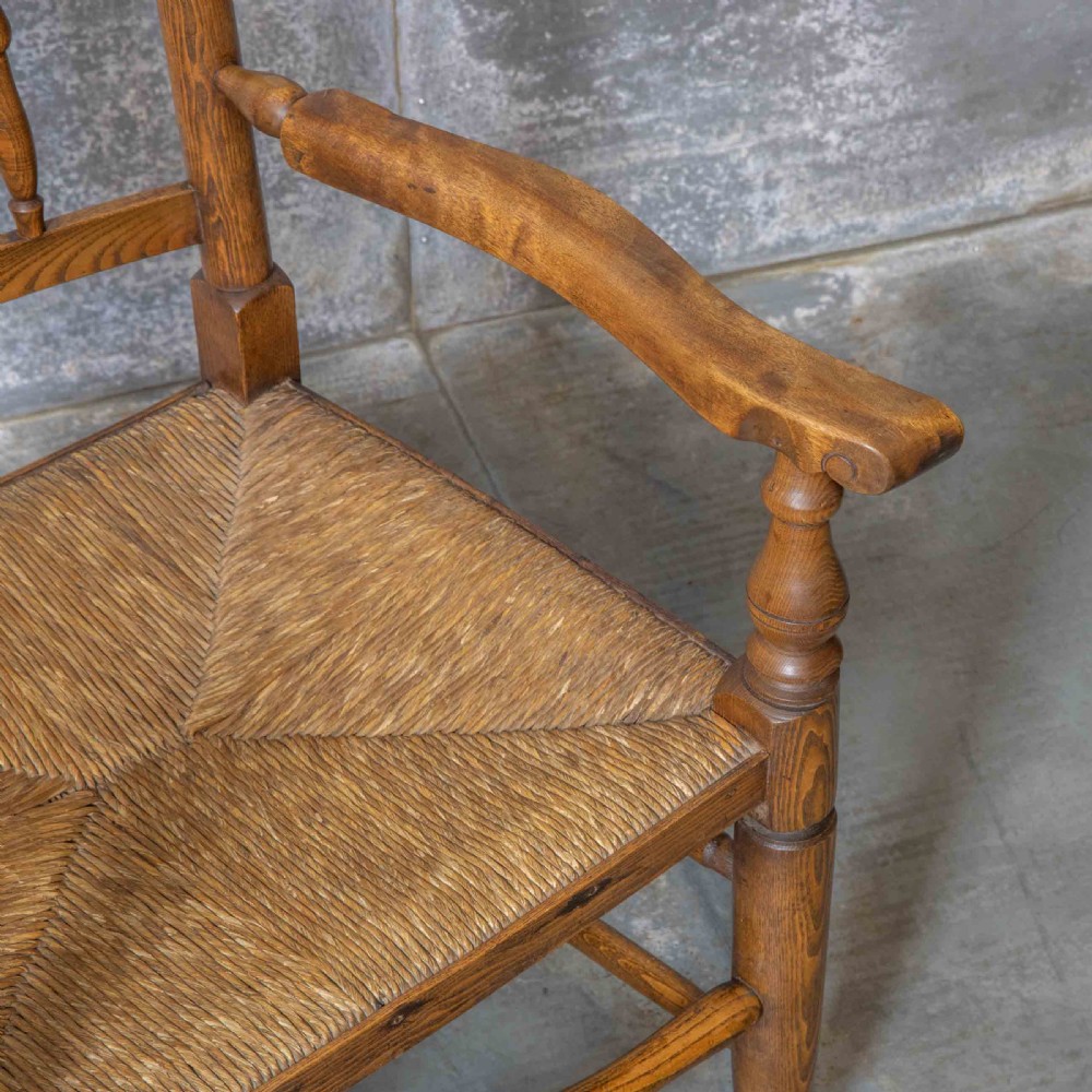A pair of matching Victorian country armchairs in warm wood with woven rush seats and turned spindle backs, including one rocking chair and one static armchair. View VI