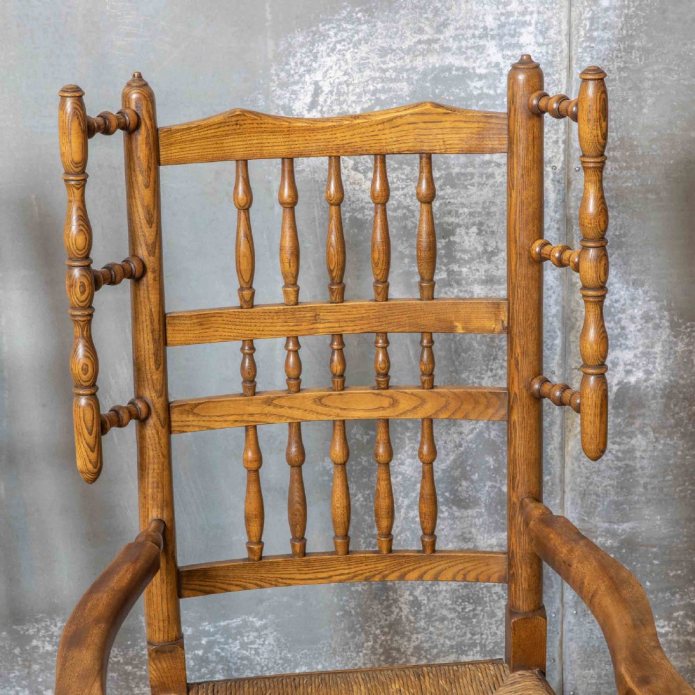 A pair of matching Victorian country armchairs in warm wood with woven rush seats and turned spindle backs, including one rocking chair and one static armchair. View IX