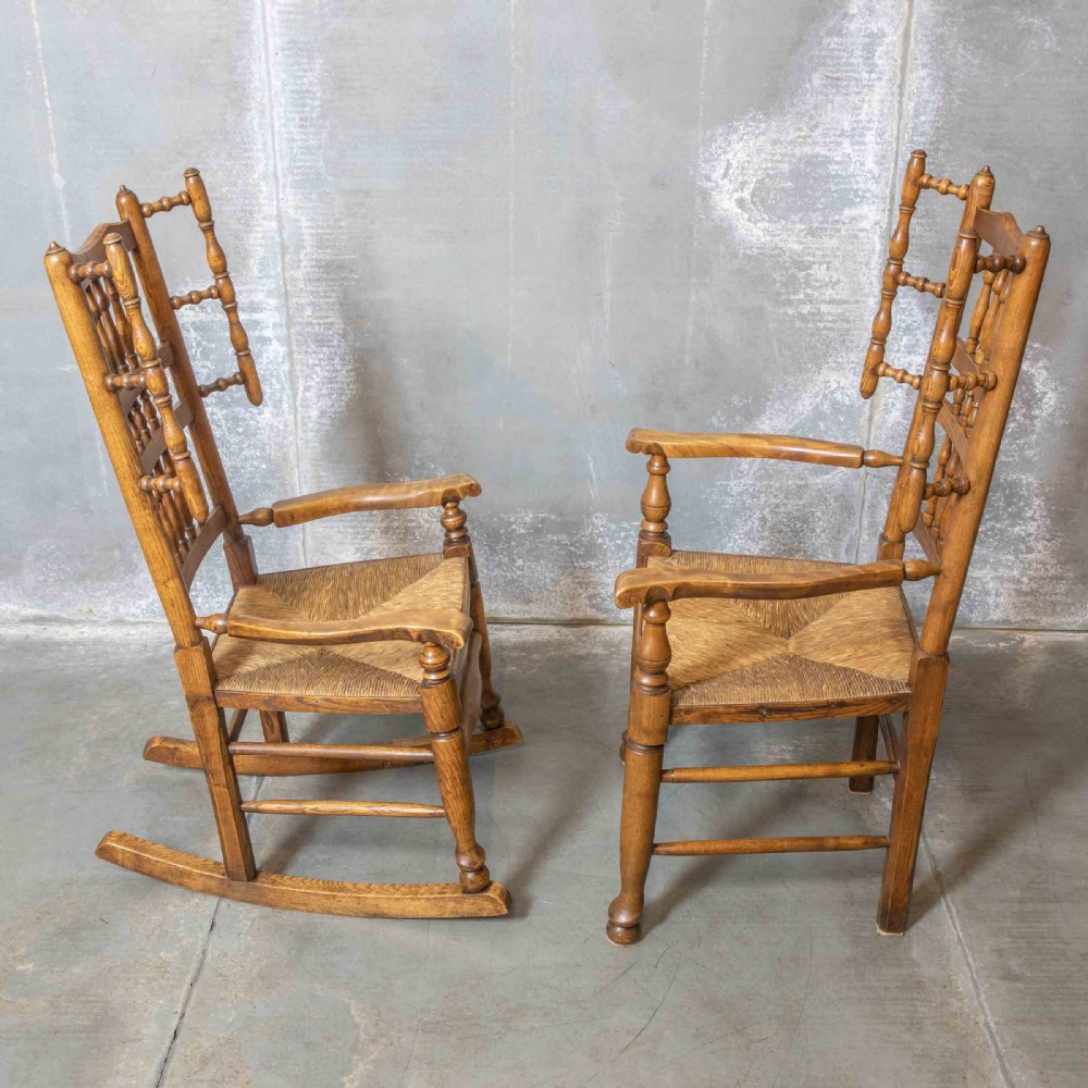 A pair of matching Victorian country armchairs in warm wood with woven rush seats and turned spindle backs, including one rocking chair and one static armchair. View X