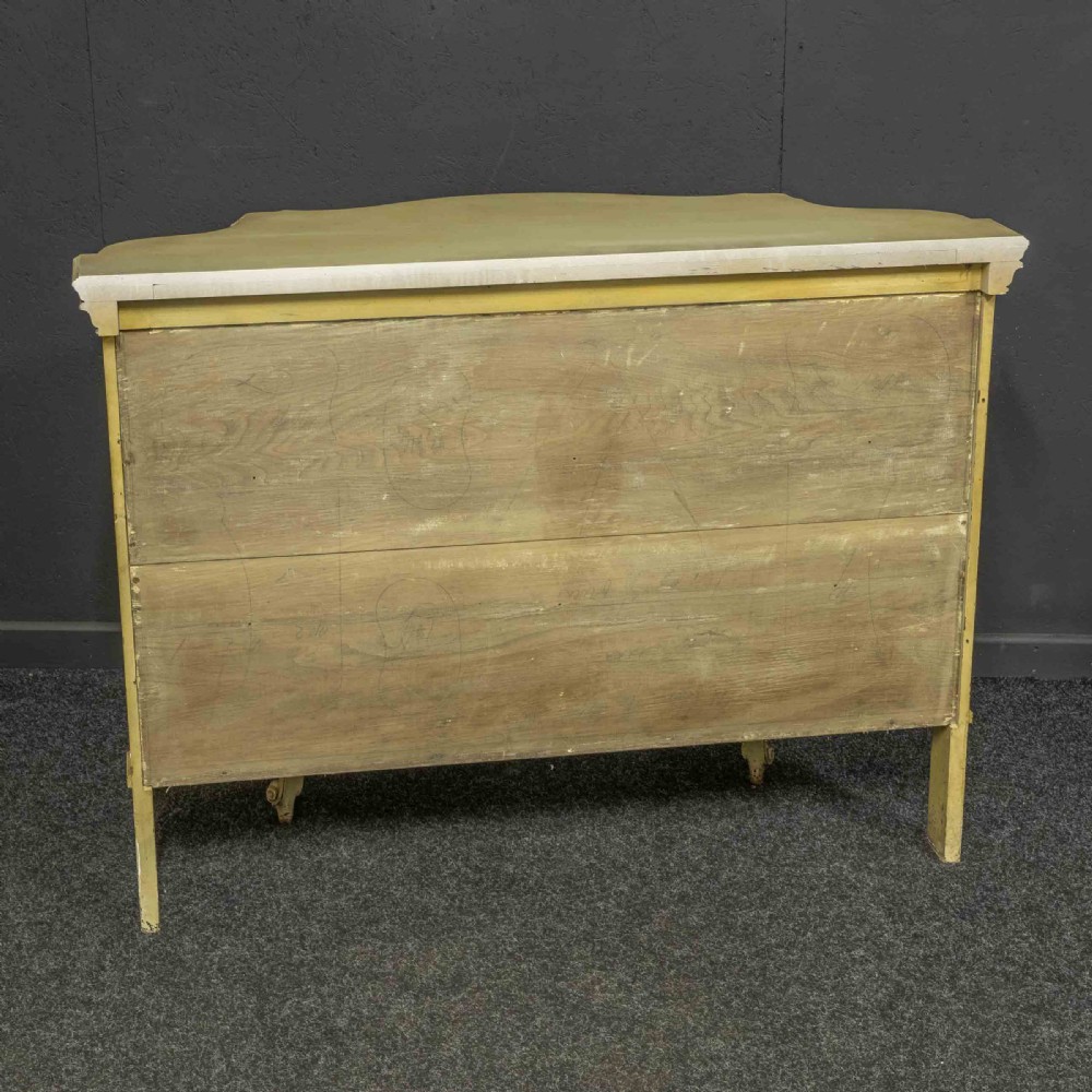 An antique cream painted serpentine credenza featuring central glazed doors, carved scroll accents, and open side shelves. View VII