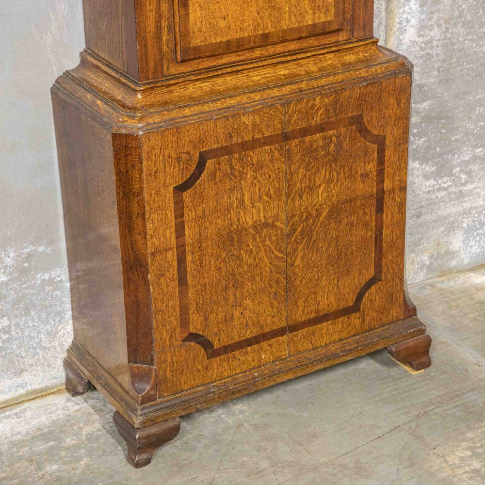 An antique Georgian oak longcase clock featuring a carved fretted pediment, brass finials, and a hand-painted square dial face. View IV