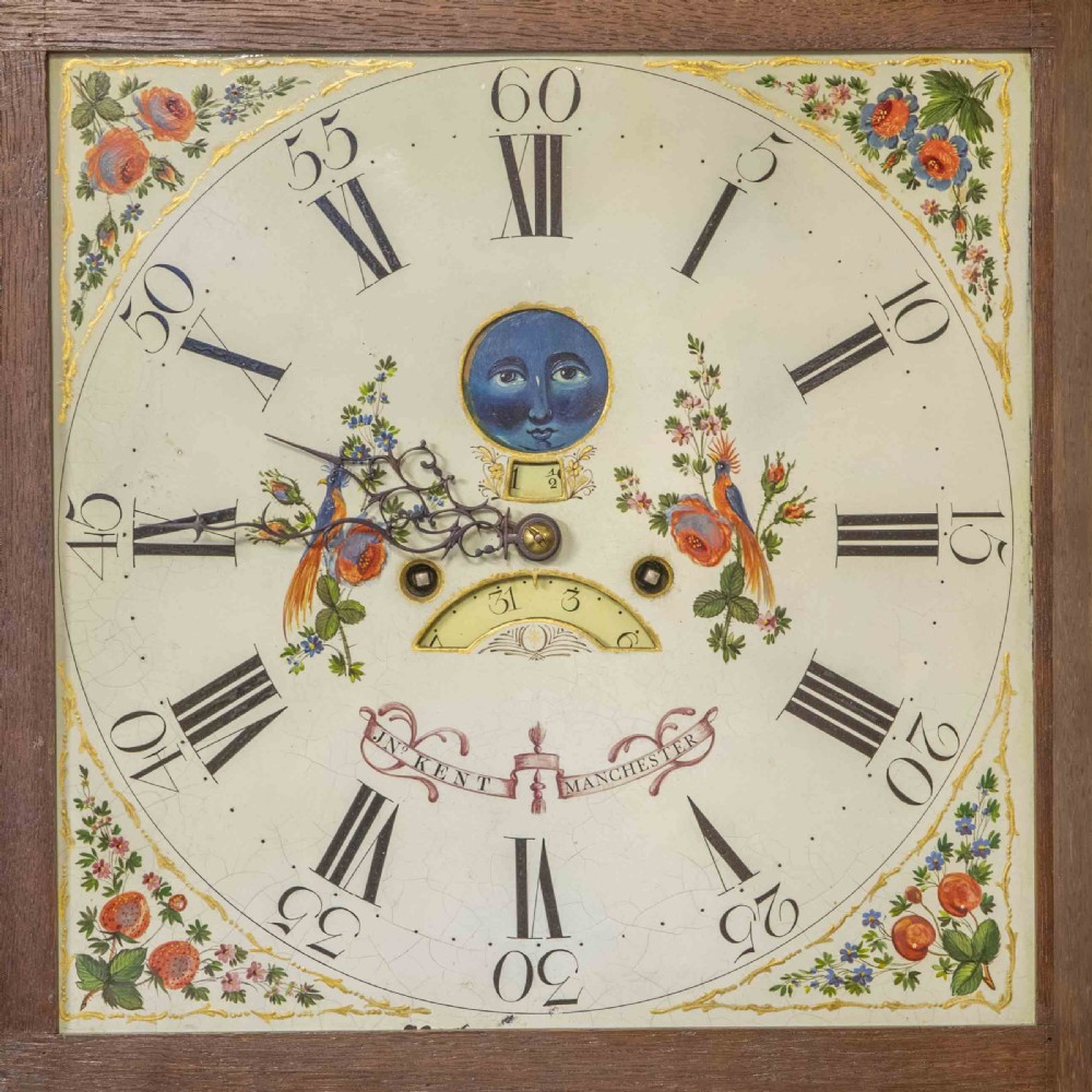 An antique Georgian oak longcase clock featuring a carved fretted pediment, brass finials, and a hand-painted square dial face. View VI