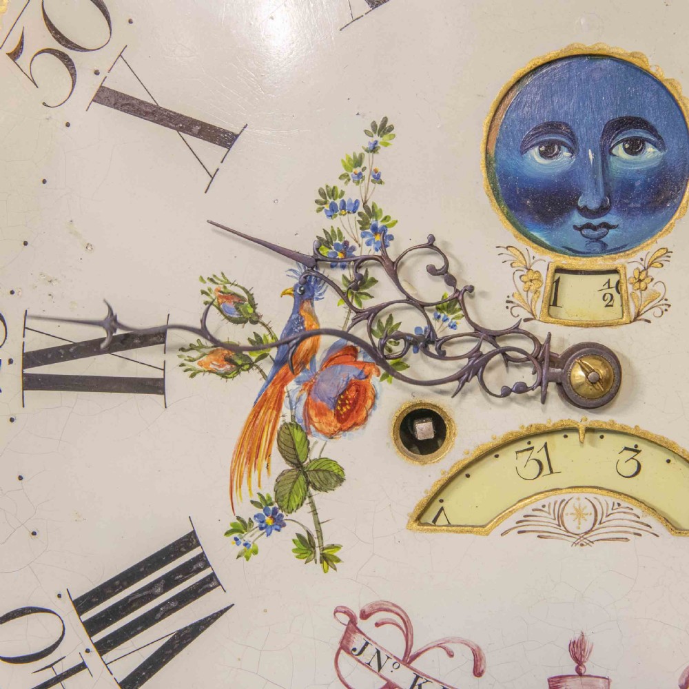 An antique Georgian oak longcase clock featuring a carved fretted pediment, brass finials, and a hand-painted square dial face. View VIII