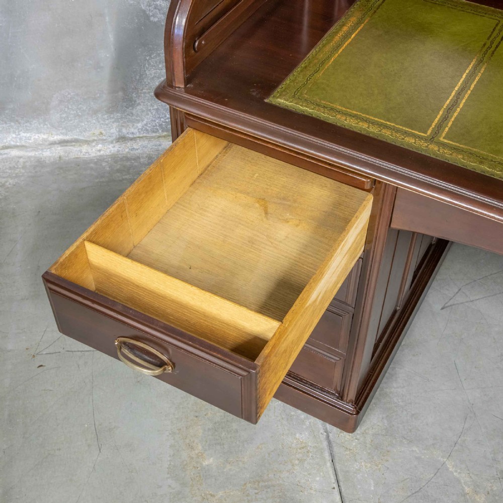 An Edwardian walnut double-pedestal roll top desk featuring a slatted tambour cover, inset green leather writing surface, multiple small interior drawers, and twin pedestal drawers with brass handles. View III