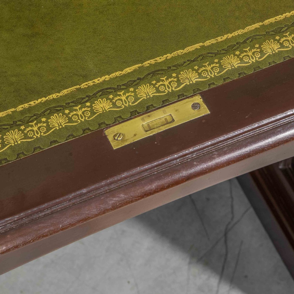 An Edwardian walnut double-pedestal roll top desk featuring a slatted tambour cover, inset green leather writing surface, multiple small interior drawers, and twin pedestal drawers with brass handles. View V