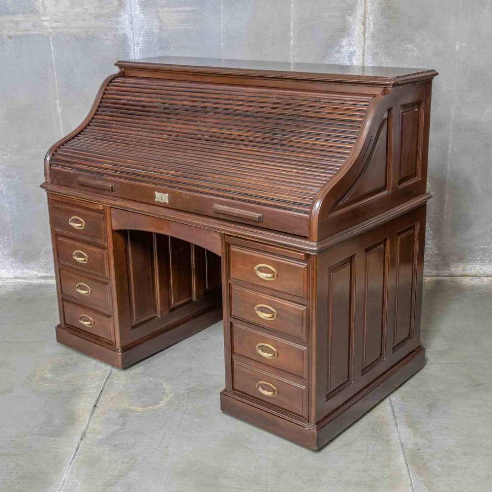 An Edwardian walnut double-pedestal roll top desk featuring a slatted tambour cover, inset green leather writing surface, multiple small interior drawers, and twin pedestal drawers with brass handles. View X