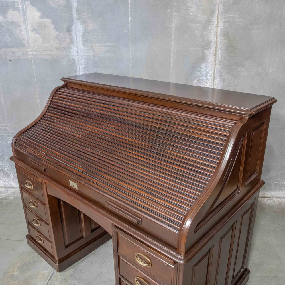 An Edwardian walnut double-pedestal roll top desk featuring a slatted tambour cover, inset green leather writing surface, multiple small interior drawers, and twin pedestal drawers with brass handles. View XI