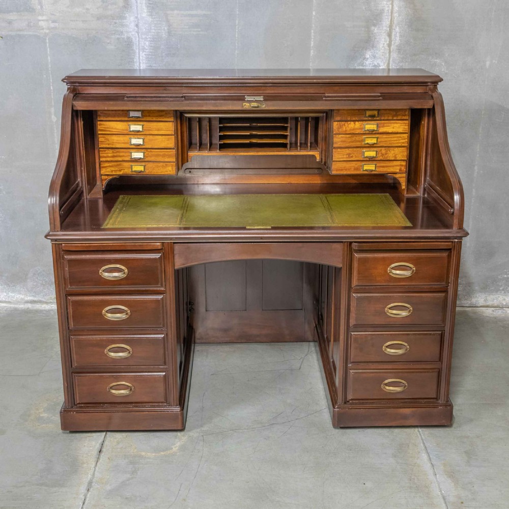 An Edwardian walnut double-pedestal roll top desk featuring a slatted tambour cover, inset green leather writing surface, multiple small interior drawers, and twin pedestal drawers with brass handles. View XIV