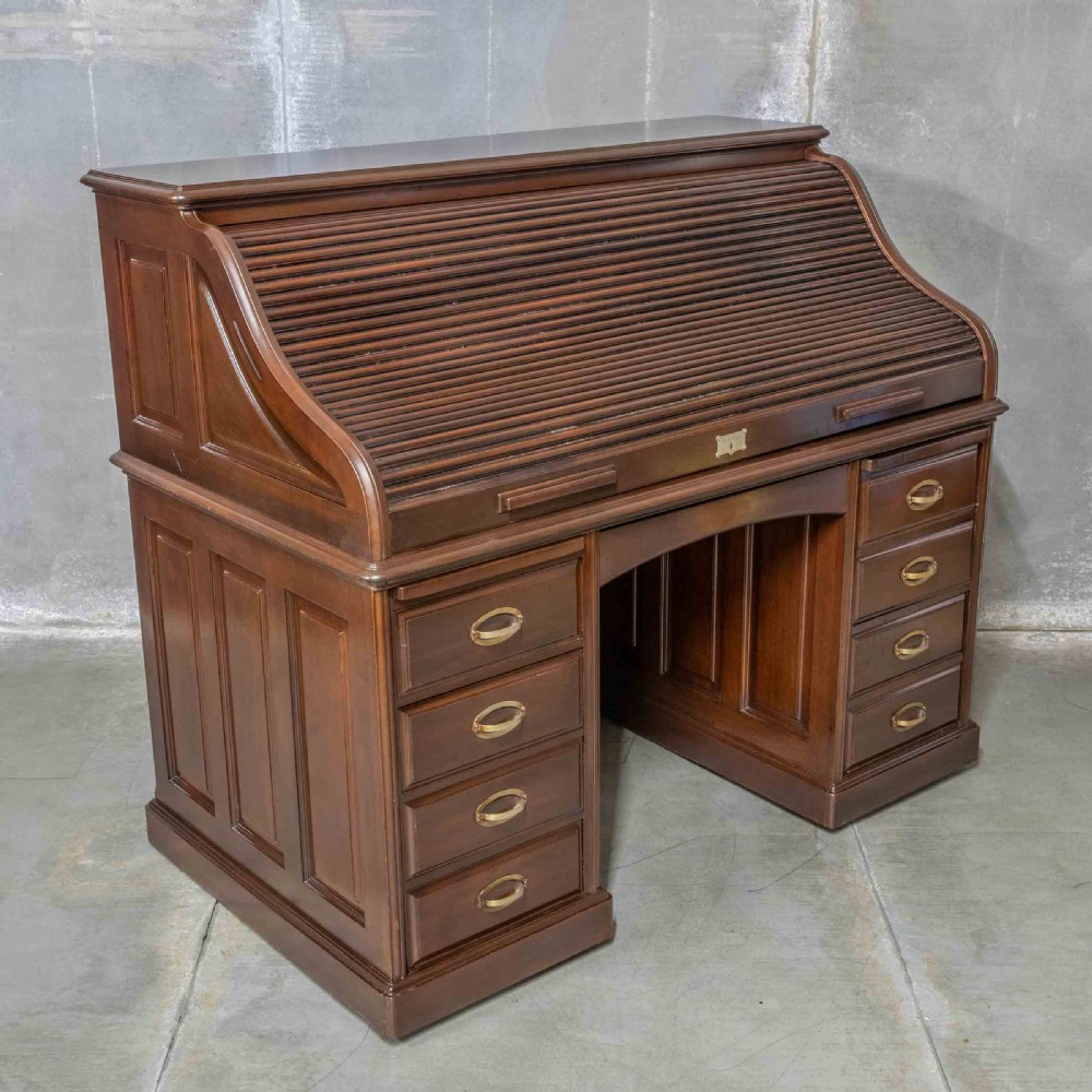 An Edwardian walnut double-pedestal roll top desk featuring a slatted tambour cover, inset green leather writing surface, multiple small interior drawers, and twin pedestal drawers with brass handles. View XVI