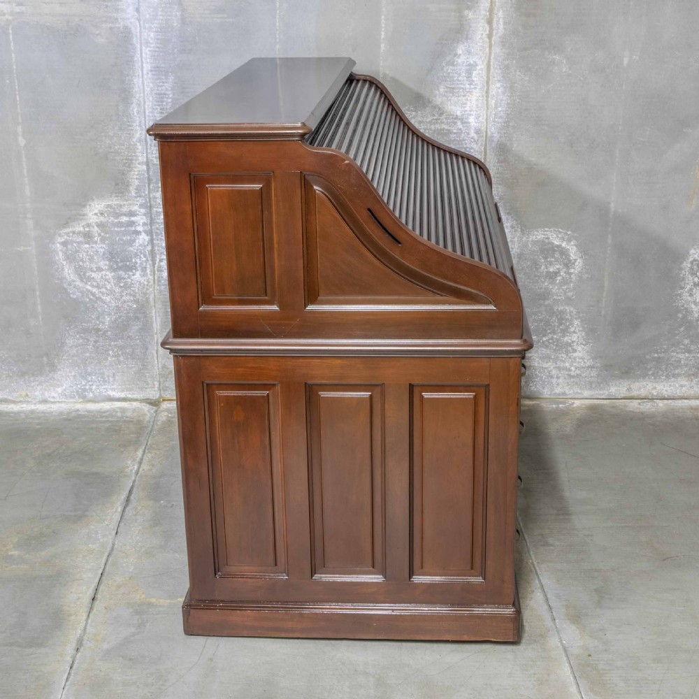 An Edwardian walnut double-pedestal roll top desk featuring a slatted tambour cover, inset green leather writing surface, multiple small interior drawers, and twin pedestal drawers with brass handles. View XVII