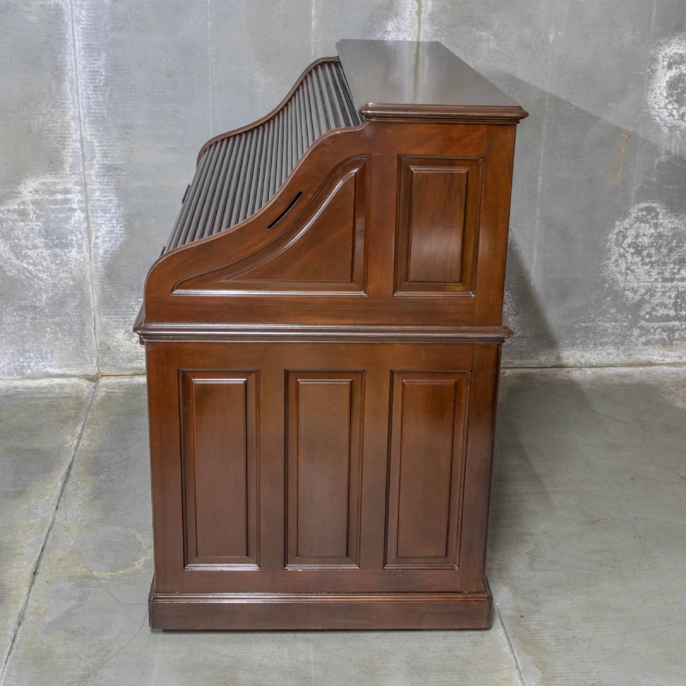 An Edwardian walnut double-pedestal roll top desk featuring a slatted tambour cover, inset green leather writing surface, multiple small interior drawers, and twin pedestal drawers with brass handles. View XIX